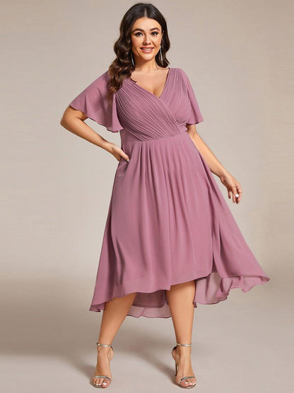 Plus-size model posing with one hand on hip in the mauve pink chiffon dress, showing the uneven high-low hemline. 66