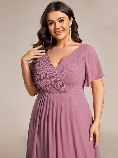 Close-up of the pleated crossover bodice and flutter sleeve in mauve pink on a plus-size model with tassel earrings. 65