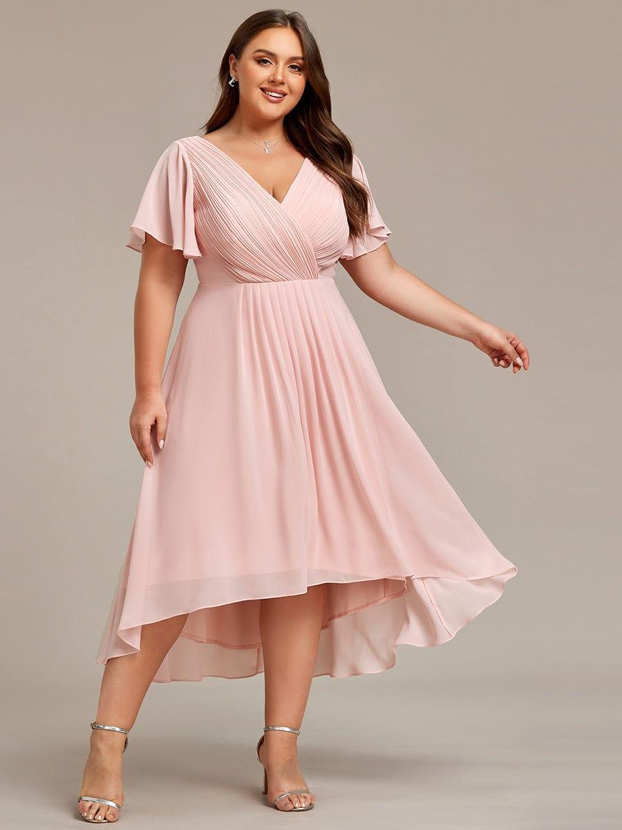 Plus-size model in the pink dress, smiling with one arm extended, showing the pleats and flowing high-low skirt. 34