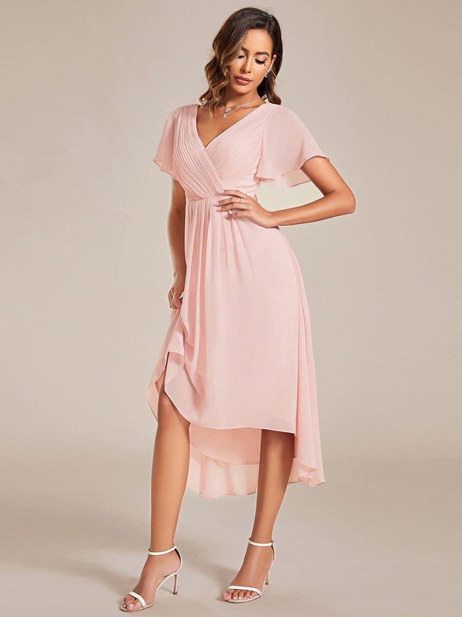 Pink dress in a side pose, the model lifting the skirt to show the layered chiffon high-low hem. 19