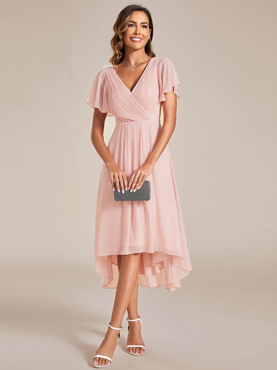 Front view of the pink chiffon dress on a model holding a small black clutch with both hands. 15