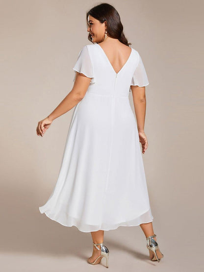 Back view of the white dress on a plus-size model, showing the V-back, zip and layered chiffon hem. 74