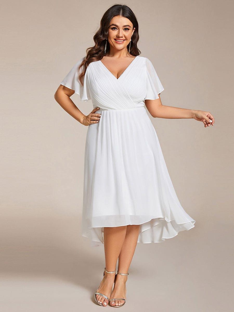 Plus-size model in the white chiffon dress with pleated V-neck, hand on hip, wearing silver strappy heels. 73