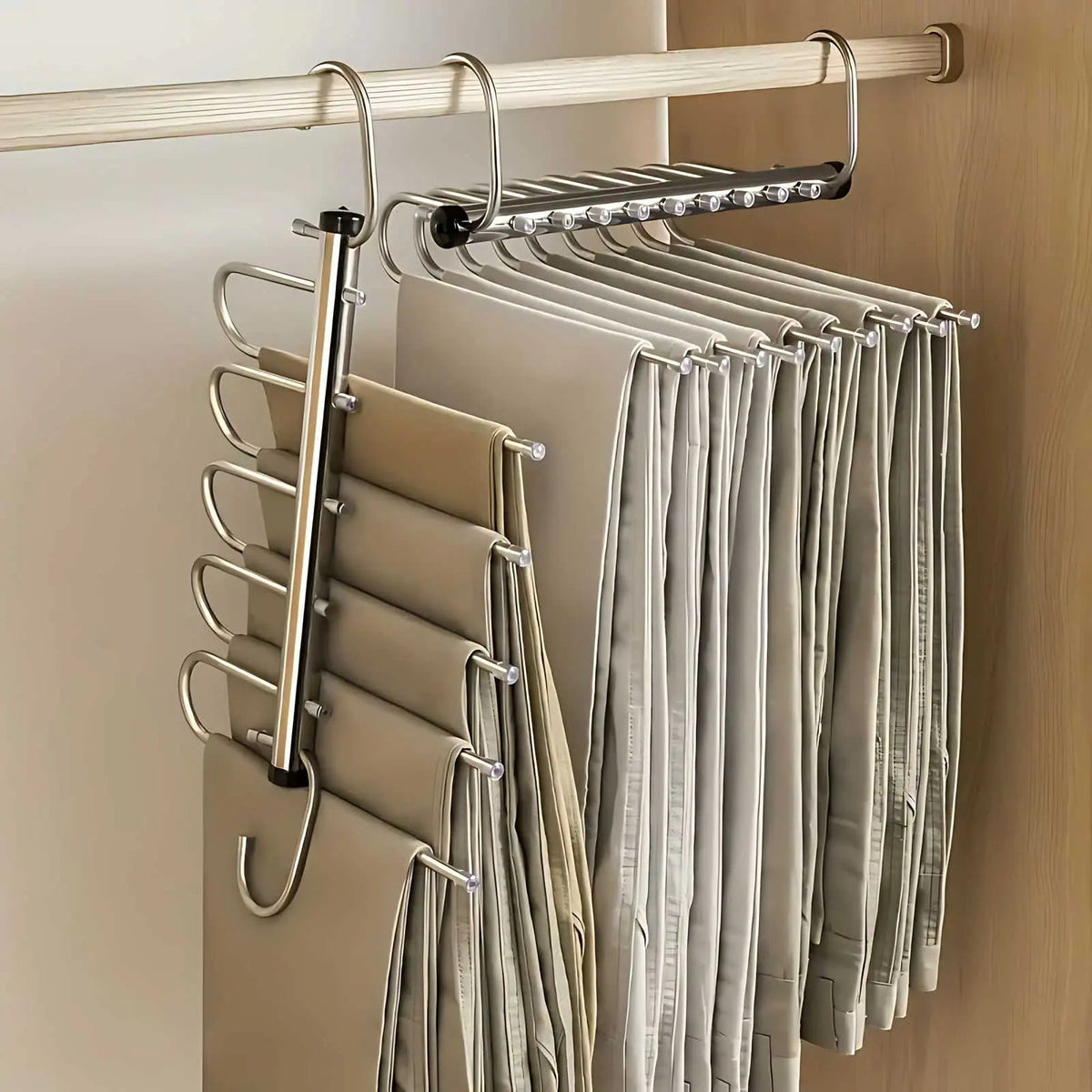 Two metal hangers on a wardrobe rail, one folded down with trousers stacked on its bars, the other opened out sideways. 1