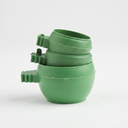 Three green plastic bowls with ridged clip handles stacked inside one another on a plain white background. 1