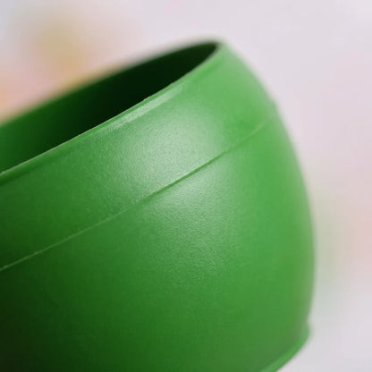 Close-up of the smooth green plastic bowl, showing its rounded curve, moulded seam and rim against a soft blurred background. 3