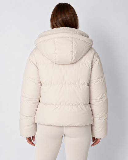 Back view of the cream puffer jacket on a model, showing the padded hood and horizontal quilting 4