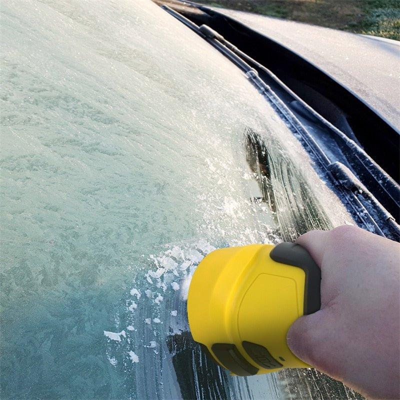 Gloved-free hand holding the yellow scraper against a frosted windscreen, with cleared ice and snow flakes beside it 2