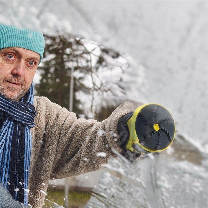 Man in a woolly hat and scarf holding the scraper's round rotating head towards a snowy windscreen 3