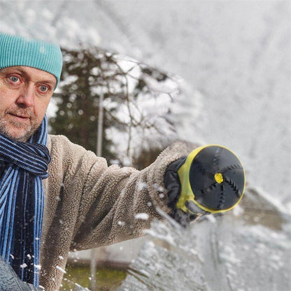 Man in a woolly hat and scarf holding the scraper's round rotating head towards a snowy windscreen 3