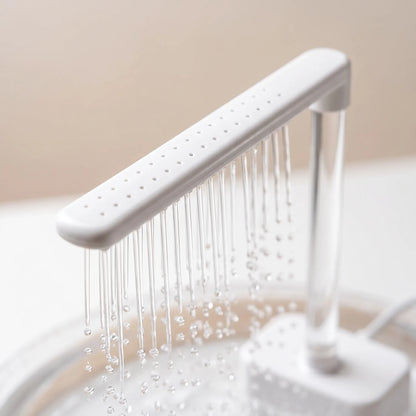 Close-up of the white spray bar with its rows of small holes and thin water streams dripping into the basin below. 3
