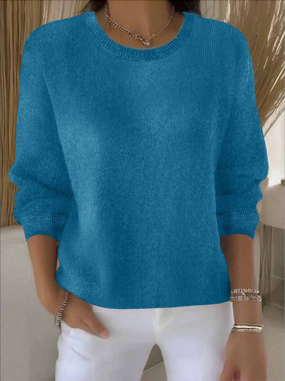 Model wears the round-neck knit jumper in teal blue with white trousers, bracelets and a chain necklace 12