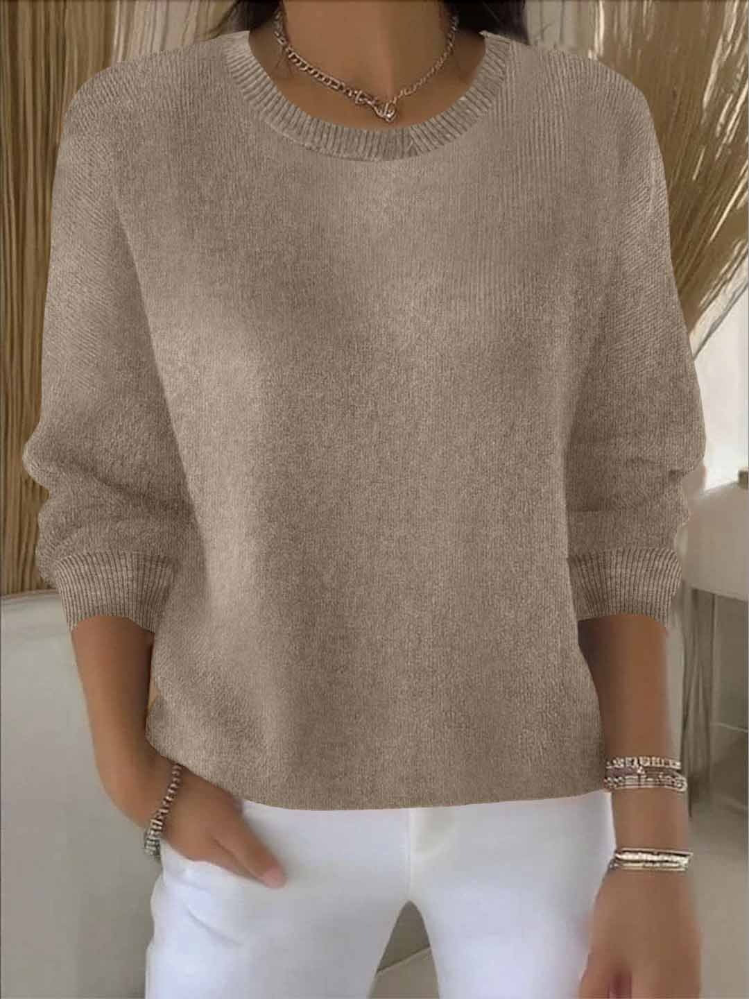 Model wears the round-neck knit jumper in taupe with white trousers, bracelets and a chain necklace 5