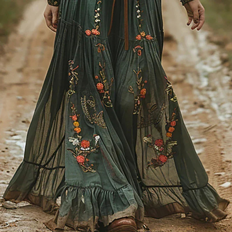 Close view of the green dress's full tiered skirt with orange and white floral embroidery and ruffled hem 2