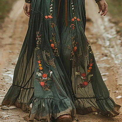 Close view of the green dress's full tiered skirt with orange and white floral embroidery and ruffled hem 2