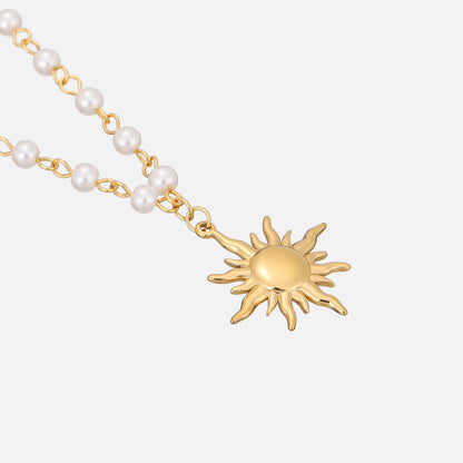 Angled close-up of the sun pendant and the pearl beads linked by small gold wire loops, laid flat. 2