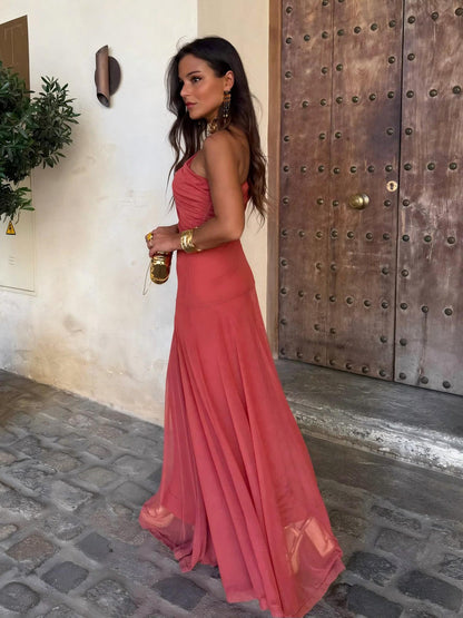 Side view of the terracotta one-shoulder dress showing the ruched bodice and flowing skirt on cobblestones 5