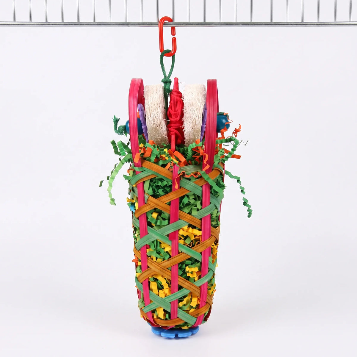 Woven basket bird toy filled with shredded paper and topped with loofah pieces, hanging from a red clip on a cage bar. 1
