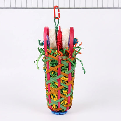 Woven basket bird toy filled with shredded paper and topped with loofah pieces, hanging from a red clip on a cage bar. 1