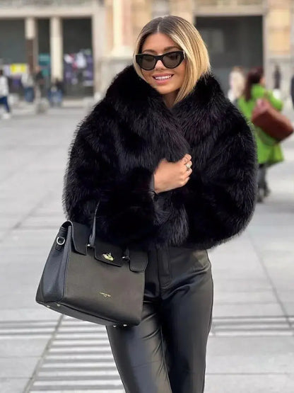 Smiling woman in sunglasses wearing a short black faux fur coat with leather trousers, outdoors 7