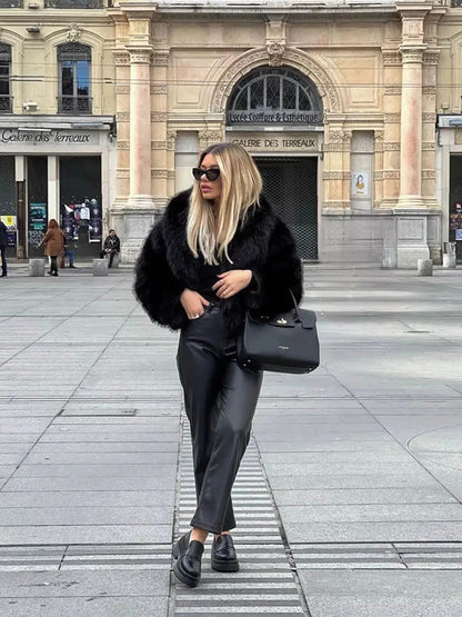 Full-length view of a woman in a black faux fur jacket, leather trousers and chunky loafers 8