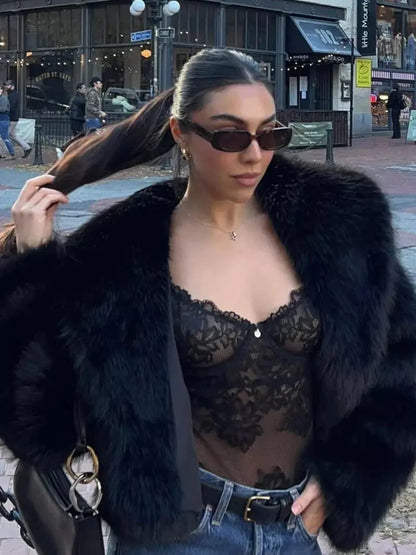 Close-up of a woman wearing the black faux fur coat open over a lace bodysuit and jeans 9