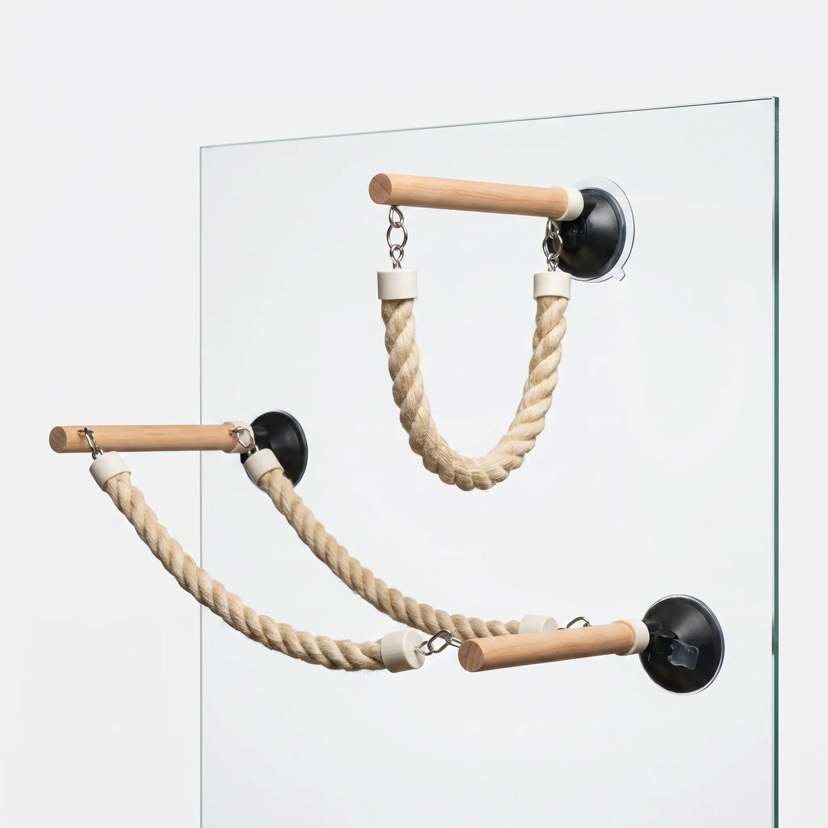 Three wooden perches with black suction cups and twisted rope loops stuck to a pane of glass at different heights. 1
