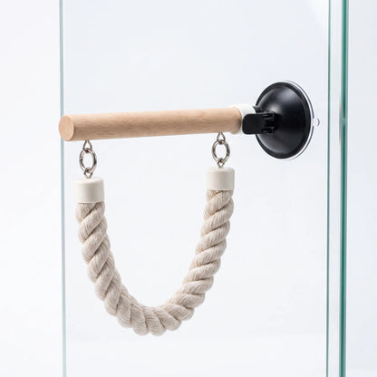 Side view of a single wooden perch on a black suction cup, with a twisted rope loop hanging beneath it on glass. 4