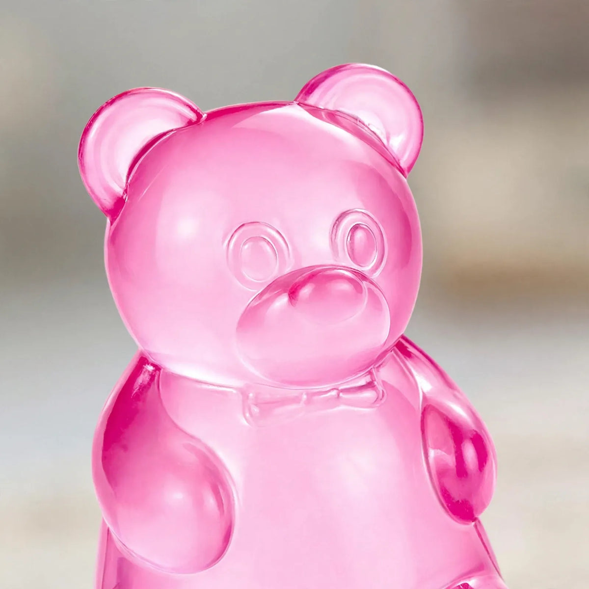 Close-up of a translucent pink gummy bear toy with a bow tie detail 3
