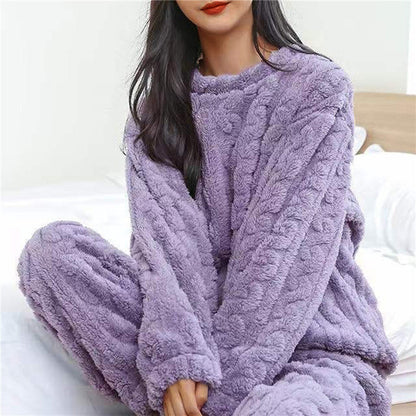 Model sitting on a bed wearing the lilac fleece pyjama top and trousers with a cable-style texture 8
