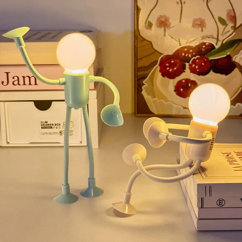 Pale green and cream figure lights lit on a shelf beside books and a framed print 3