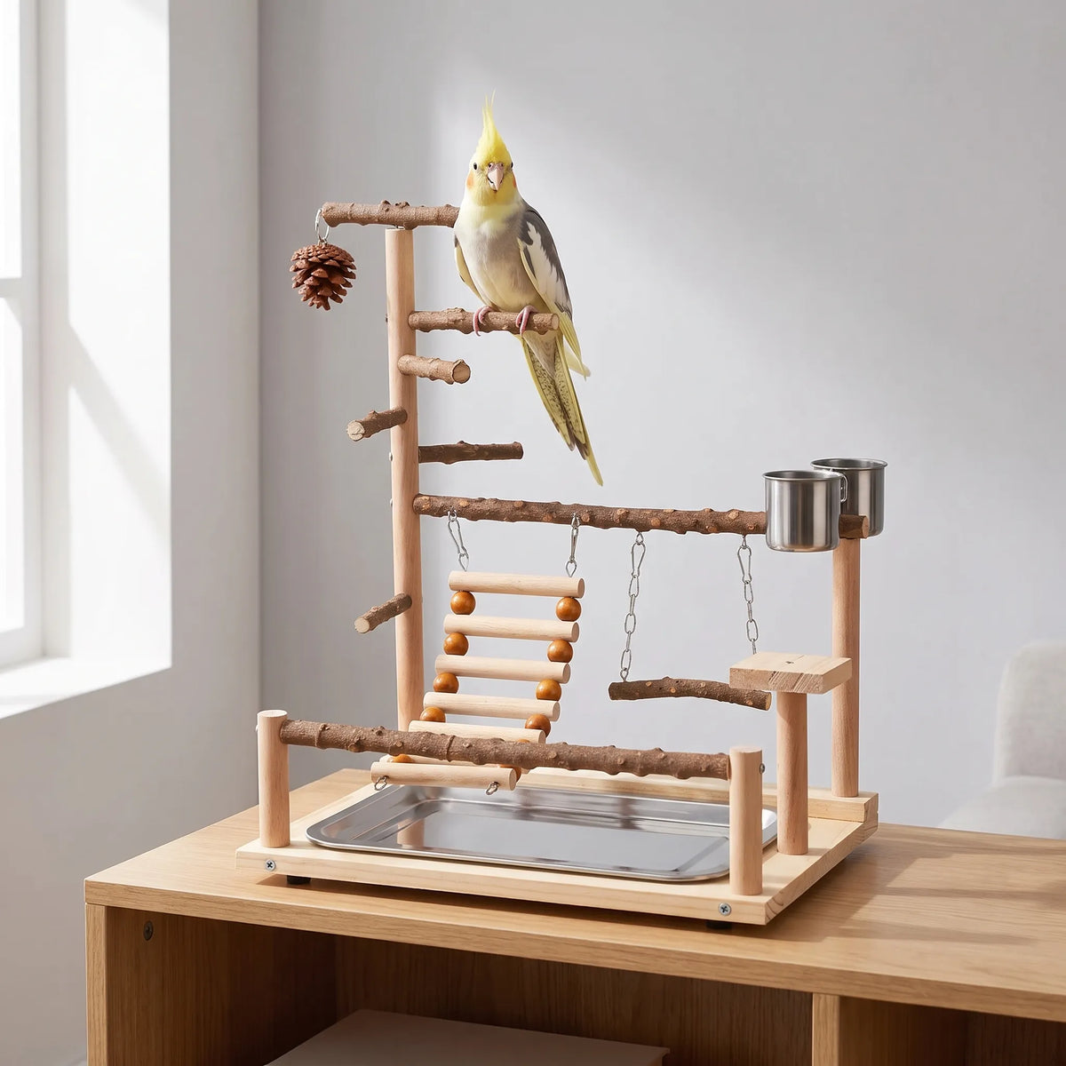 Playground standing on a wooden shelf in a bright room, with a yellow and grey cockatiel perched on the top branch. 2