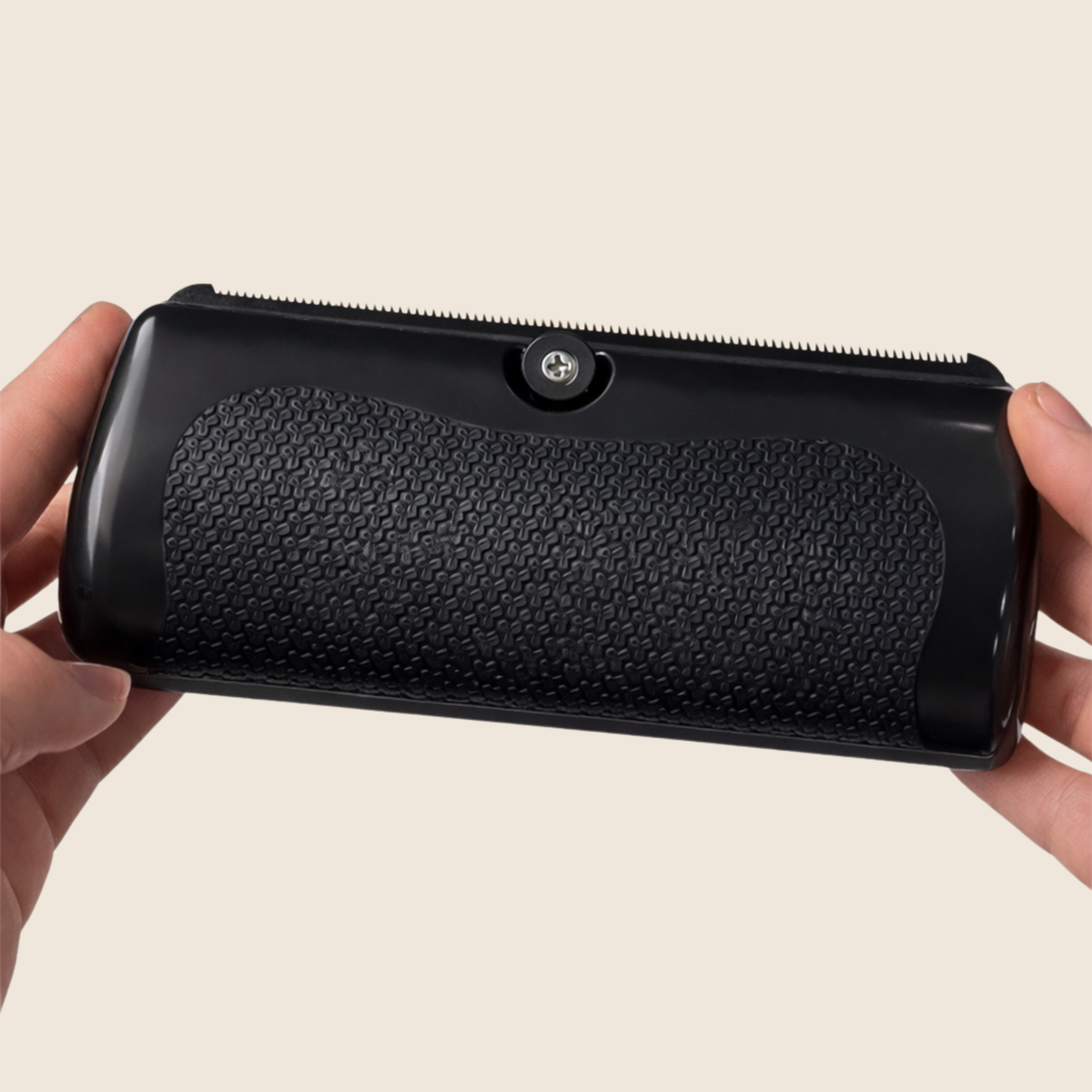 Back of the black brush held in two hands, showing the textured non-slip grip panel and the screw at the top. 3