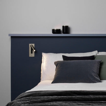 Bronze wall light fitted on a navy headboard panel above grey and white bedding 30
