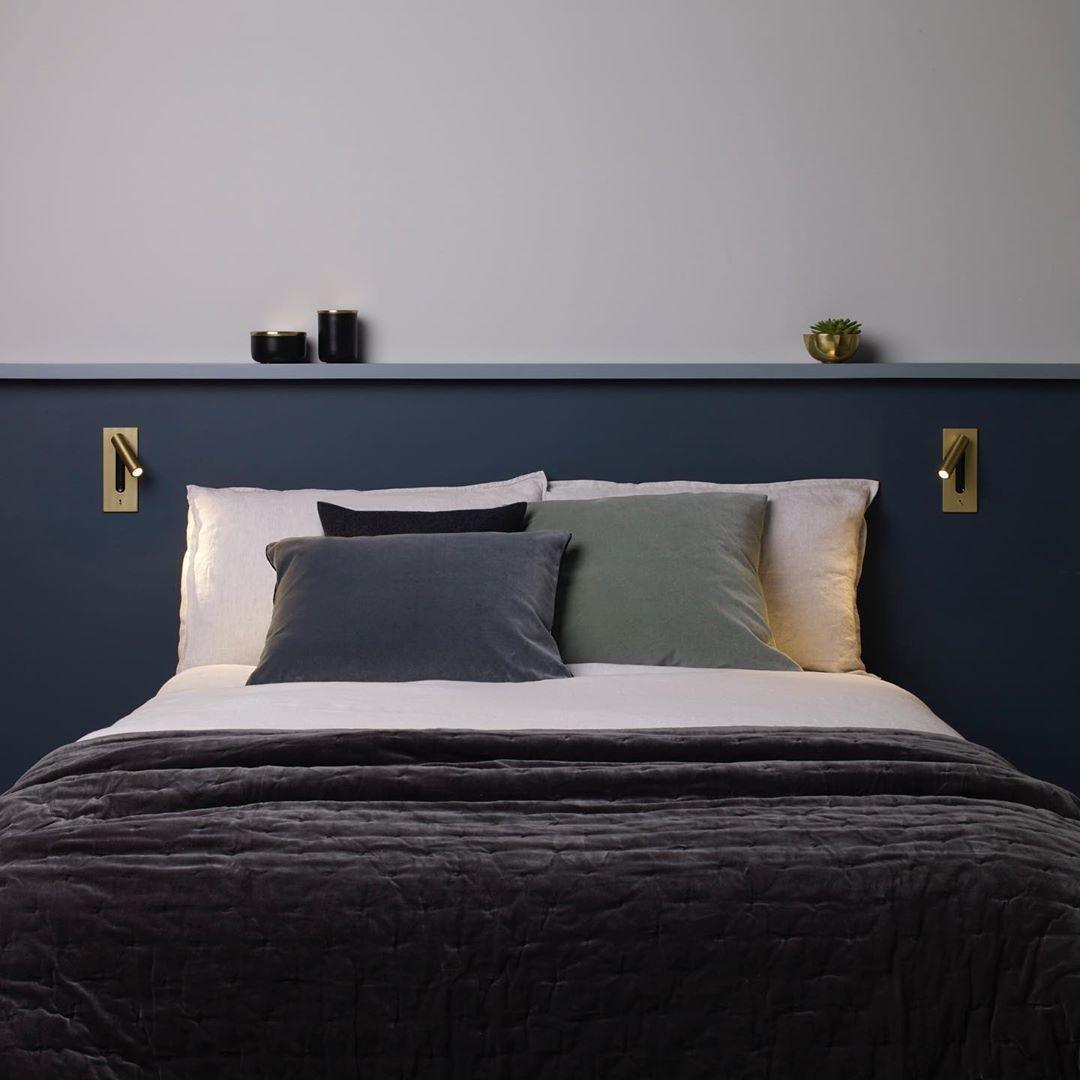Pair of gold wall lights either side of a bed on a navy headboard 35
