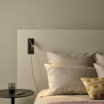 Bronze wall light with a charging cable trailing down to a phone on a bedside table 36
