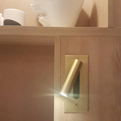 Gold wall light fitted into pale wood shelving, its LED tube casting a bright beam 32