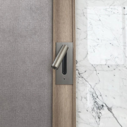 Nickel finish wall light set into a wooden strip between grey fabric and white marble 33