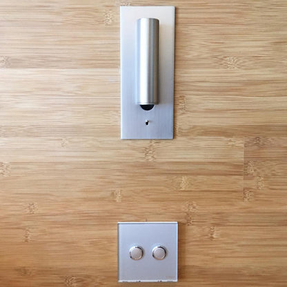 Silver wall light with the tube folded upright against its plate, above a two-button switch on bamboo 34