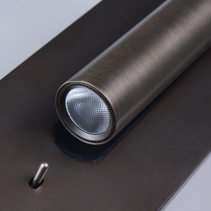 Bronze wall light on a white wall, lit tube angled right with the black recess visible 18