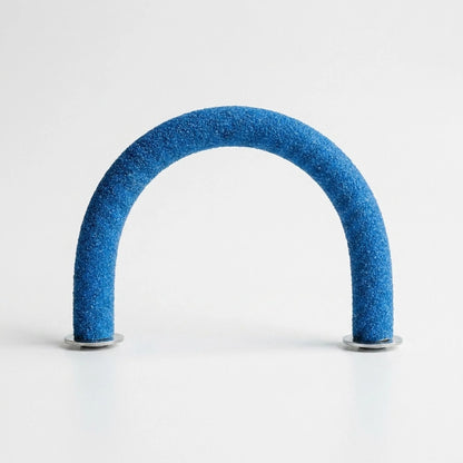 Blue gritty-textured curved perch standing upright in an arch on two metal washers against a plain white background. 1