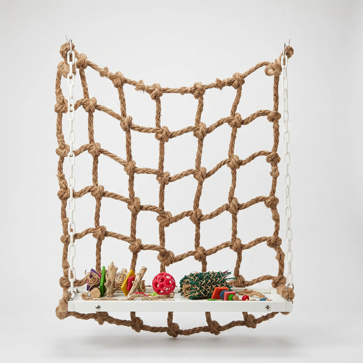 Rope climbing net hung on white plastic chains from hooks, with a white wooden platform holding colourful toys, against a plain background. 1
