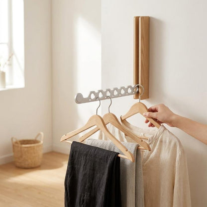 Light oak rack on a white wall with its silver-toned arm out, a hand hanging a linen shirt beside trousers. 3