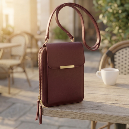 Burgundy version of the flap crossbody bag with gold bar clasp and double zips, standing on a rustic wooden table. 6