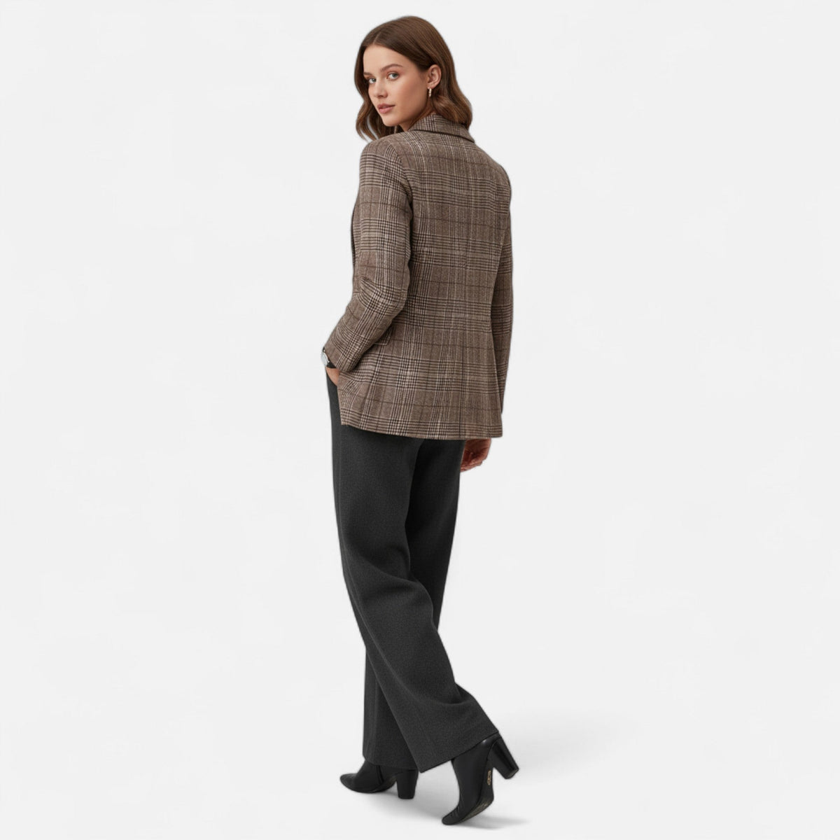 Model seen from behind and looking over her shoulder, showing the back of the check blazer with grey trousers and black boots. 3