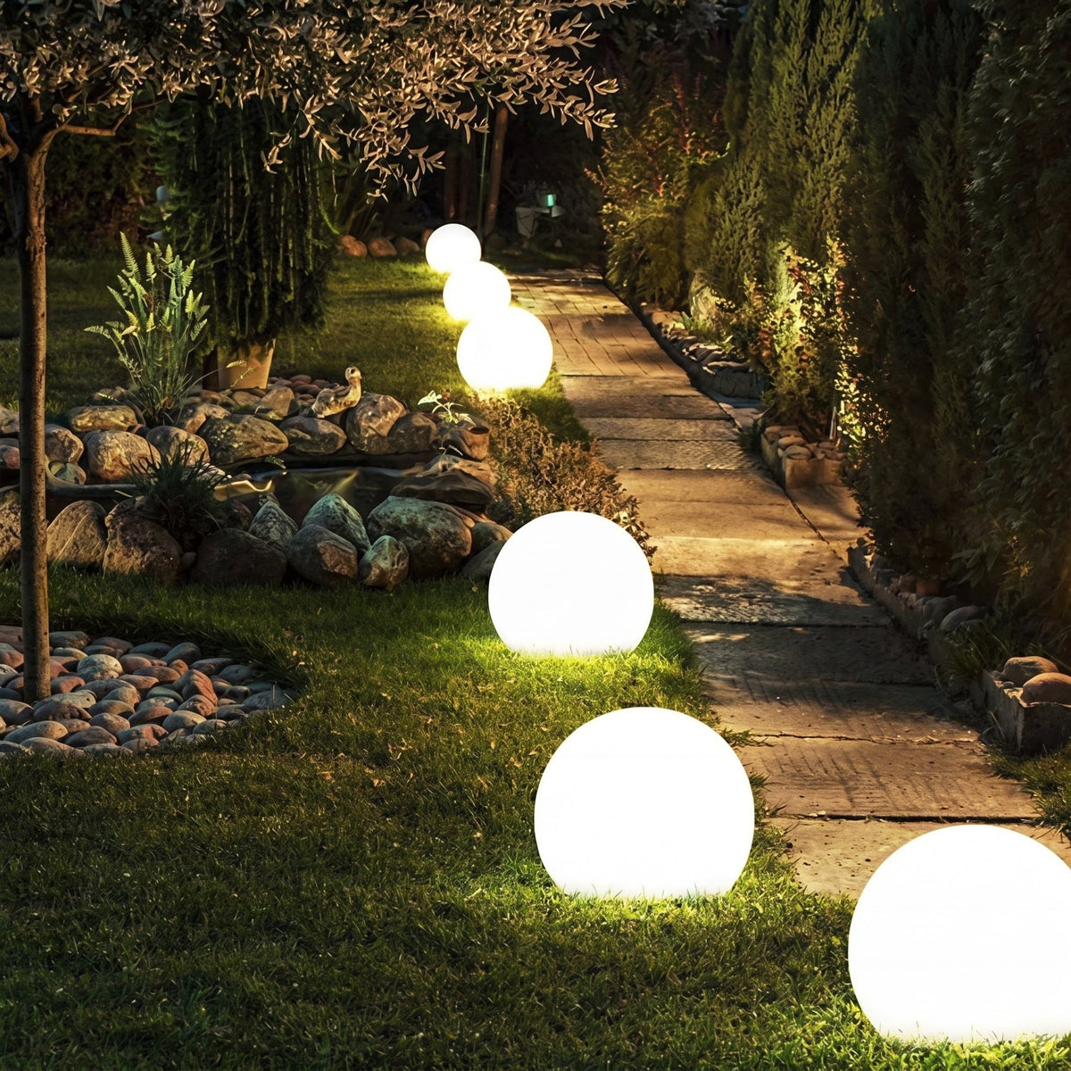 Evening garden path edged with glowing spheres of varying sizes on the grass, stretching away between rockery stones and tall hedges. 6