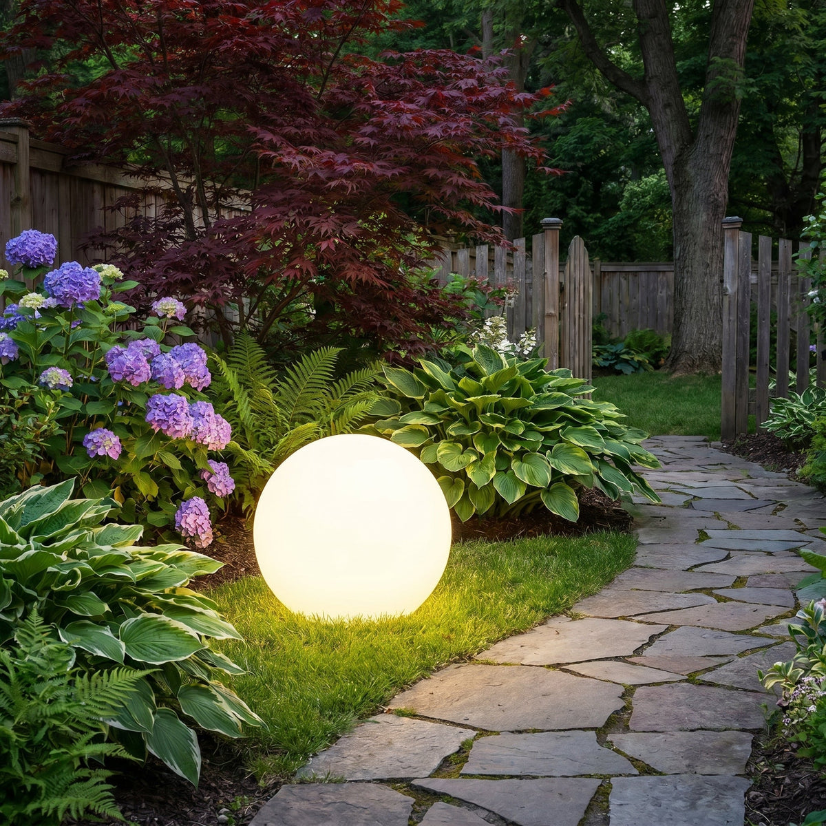 A single large glowing sphere on a lawn beside a flagstone path, with hydrangeas and hostas around it at dusk. 3