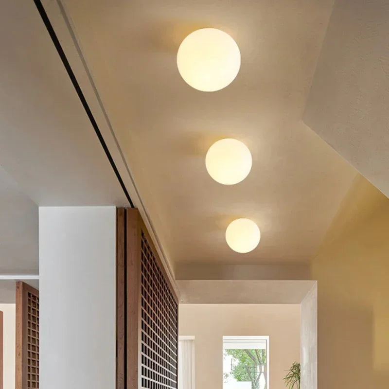 Three opal glass spheres of graduated sizes lit in a row along a corridor ceiling 9