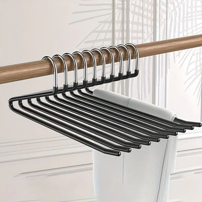 Row of black Z-shaped hangers on a wooden rail, holding a pair of white trousers 1