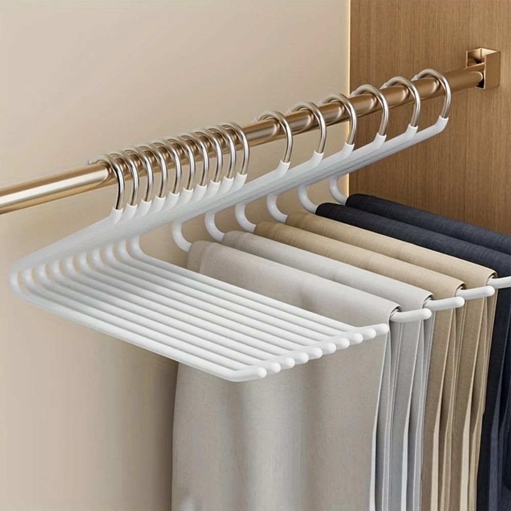 White Z-shaped hangers on a gold wardrobe rail, holding beige, grey and navy trousers 3